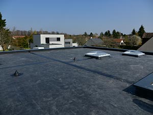 EPDM-Roofing-Elizabethtown-KY-Kentucky-2 | Commercial Roofing Pros Flat rooftop with two rectangular skylights and vents, with a low parapet and a suburban neighborhood in the background