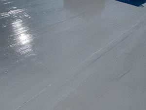 Rubber-Roof-Coating-Campbellsville-KY-Kentucky-2 | Commercial Roofing Pros Sunlit light-gray concrete surface with glare reflections from the sun.