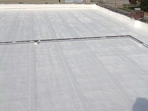 Flat, white-coated flat roof with visible seams and edges, likely reflective roofing material on a building roof.